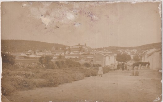 Antigua Postal. Entrada a una Población (?) Se ve el Castillo al fondo